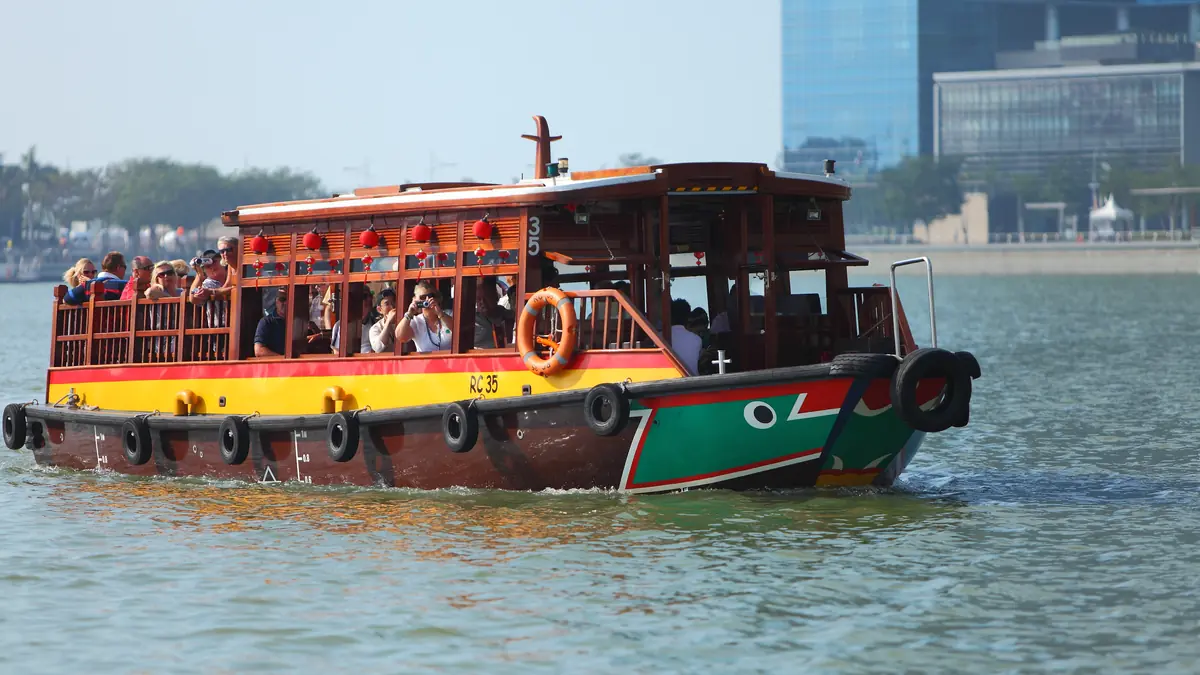 Clarke Quay — A traditional wooden bumboat carrying passengers on a Singapore River cruise past the CBD