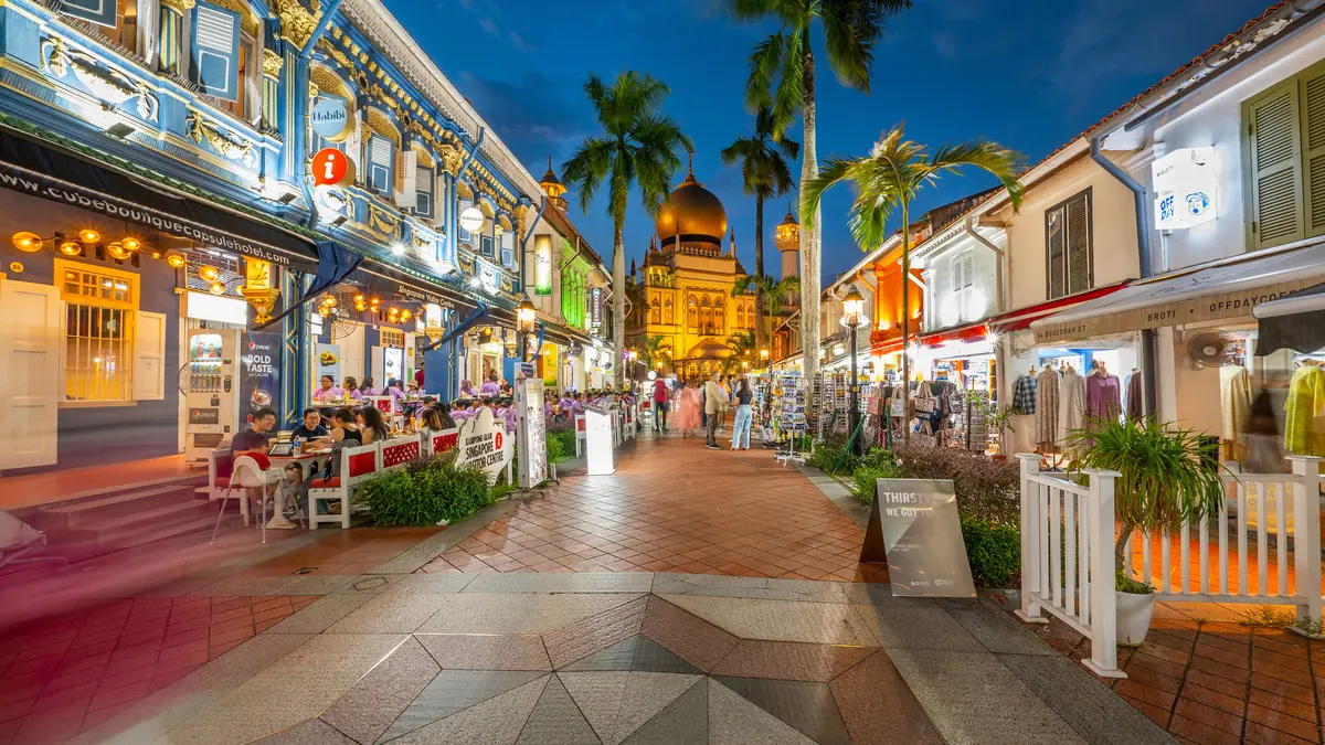 Bussorah Street in Kampong Glam at dusk, its palm-lined pedestrian mall leading to Sultan Mosque