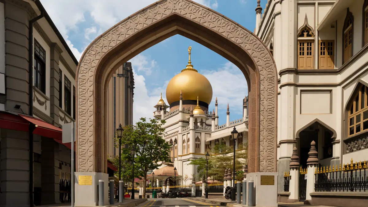 Kampong Glam — The golden dome of Sultan Mosque framed through an ornate Moorish archway in Kampong Glam