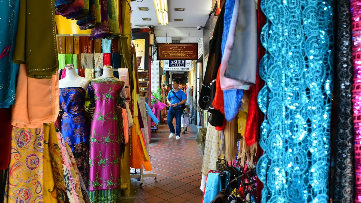 Kampong Glam — Bolts of brightly coloured fabric and traditional garments hanging outside a textile shop on Arab Street