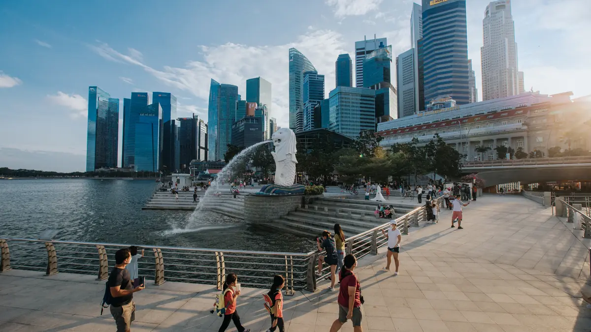 Merlion Park — Visitors on the Merlion Park promenade in daylight with the Merlion spouting into Marina Bay and the CBD behind