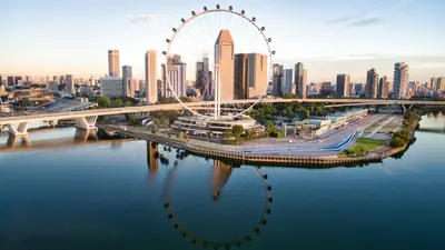Singapore Flyer — The Singapore Flyer observation wheel and the city skyline reflected in the water at sunrise