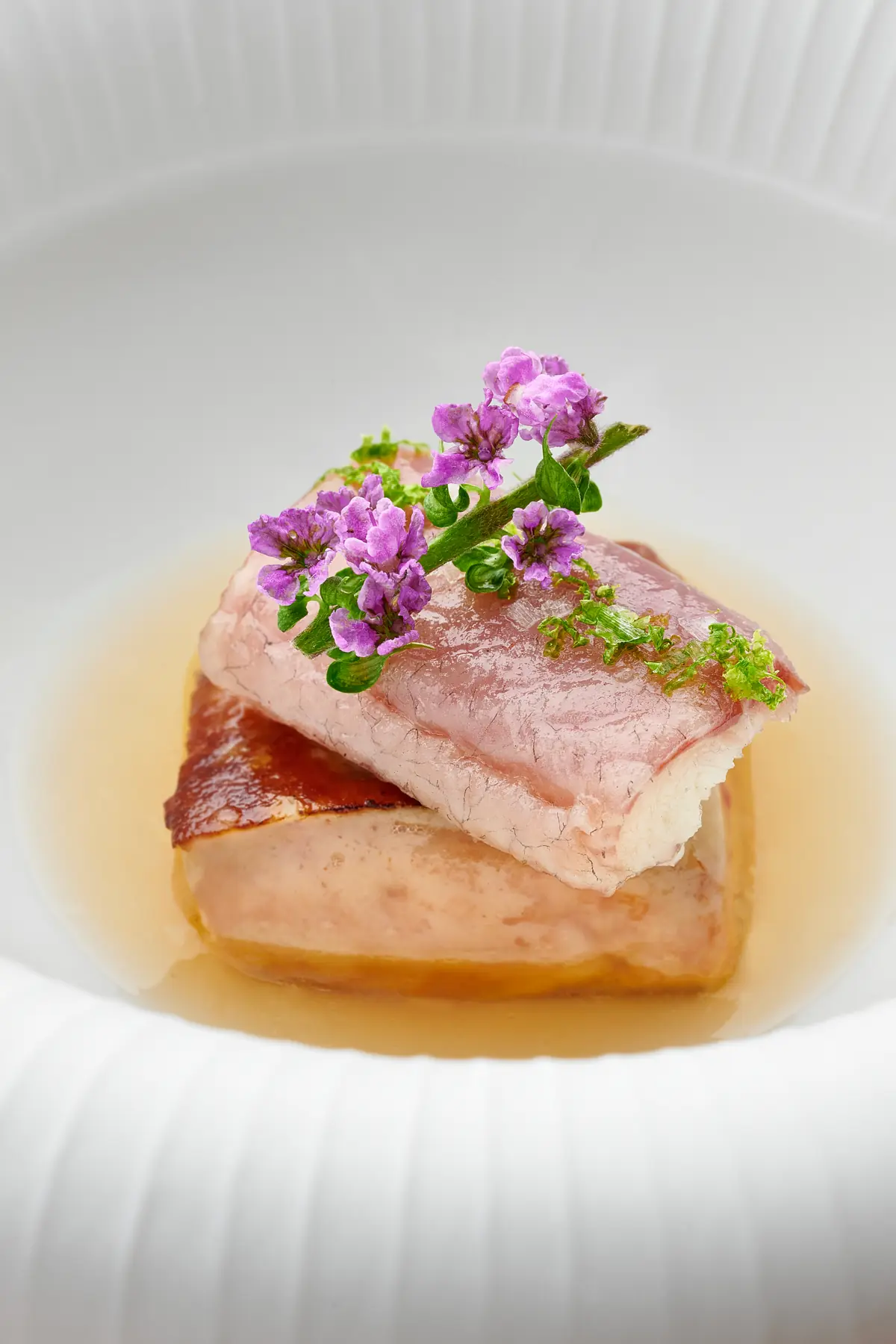 A plated fish course with edible flowers at Araya, Singapore