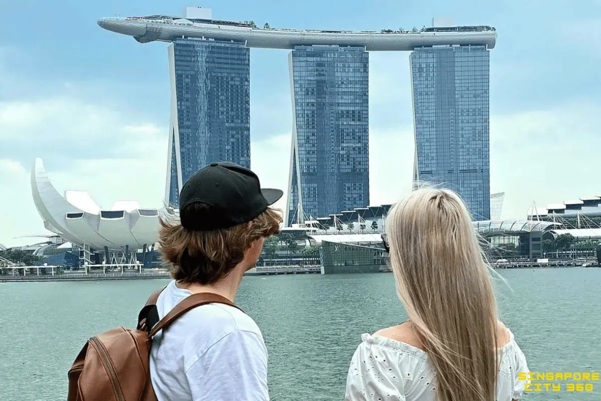 Couple at Marina Bay Sands with the hotel's three towers and SkyPark above them